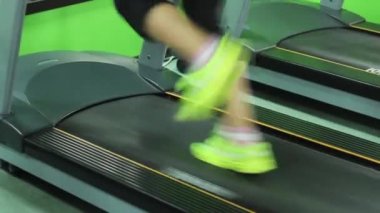 Sarı spor ayakkabı koşu bandı üzerinde çalışan kız.
