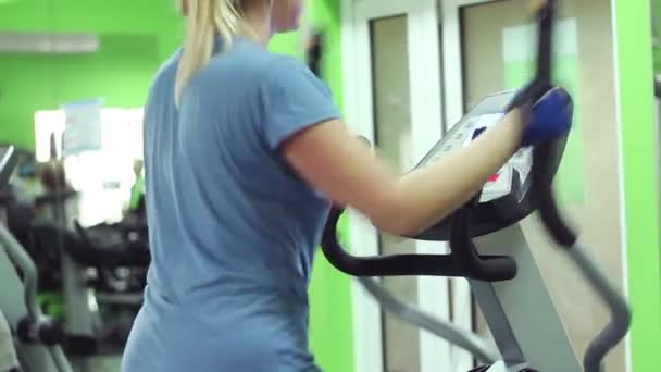 Meisje in een blauw shirt is betrokken bij de sportschool. Hij wil om gewicht te verliezen. — Stockvideo