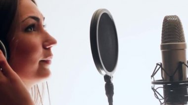 Güzel şarkıcı bir şarkı bir kayıt stüdyosunda kaydedildi. Bir şarkı ayakta kulaklıktan şarkı söylüyor.