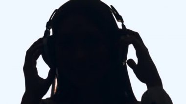 Güzel kız Dj kulaklık müzik ve dans. Arkadan aydınlatmalı bir kız. DJ siluet.