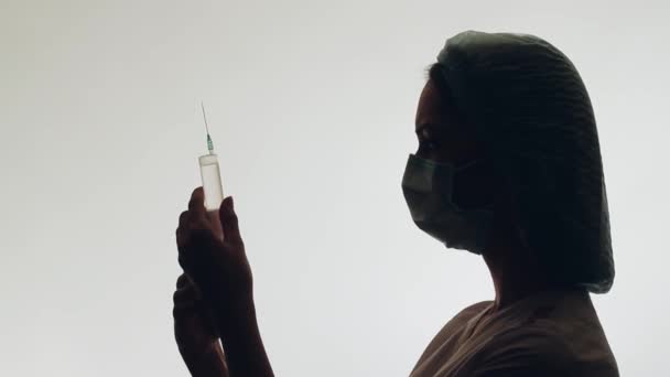 L'infirmière prépare une injection. Elle tient une seringue. Silhouette de la fille . — Video