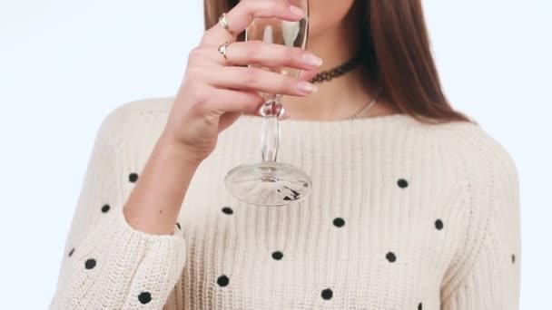 Hermosa chica bebiendo vino de una copa y sonrisas encantadoras. Una chica de pie sobre un fondo blanco. Año Nuevo — Vídeos de Stock