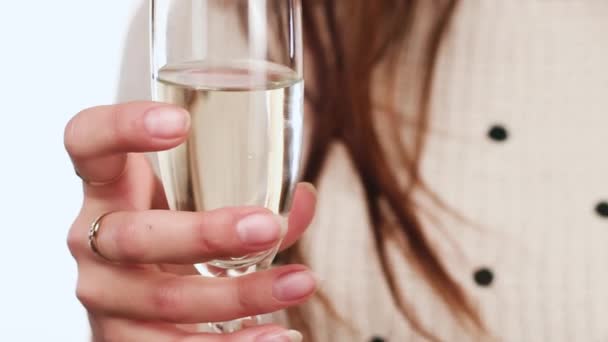 Mooi meisje permanent met een glas champagne in de hand. Een meisje permanent op een witte achtergrond glimlachen. Ze is heel schattig. — Stockvideo