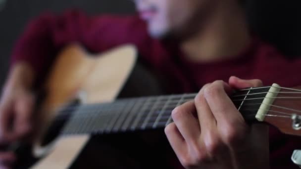 Un músico talentoso tocando la guitarra acústica en la oscuridad. El tipo cantando y tocando. Primer plano . — Vídeos de Stock