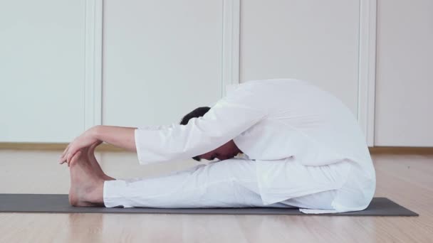 Schöner Mann praktiziert Yoga in einem Studio. Paschimottanasana. — Stockvideo