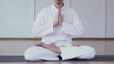 Beyaz giyinmiş bir adam uygulamaları Yoga. Kollarını ve namaste meditasyon katlanmış. Ardha Padmasana