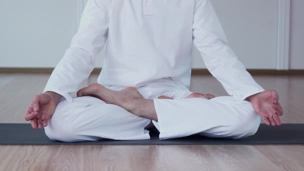Человек практикует йогу в студии йоги. Он сидит в Ардха Падмасане и медитирует. . — стоковое видео