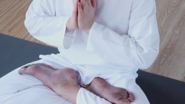 Человек практикует йогу. Ардха Падмасана. Йоги медитирует в позе лотоса, сидя на коврике для йоги . — стоковое видео