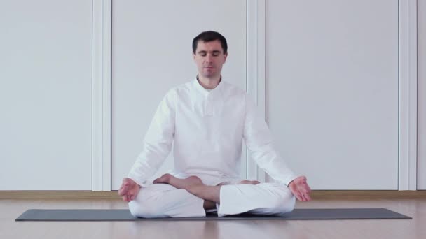 Przystojny mężczyzna praktykowania jogi w studio jogi. Ardha Padmasana. — Wideo stockowe