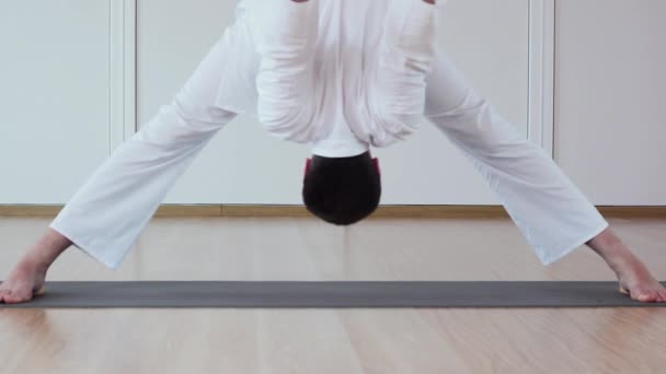 Lindo hombre haciendo yoga. Padottanasana — Vídeos de Stock