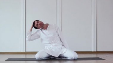Şirin çocuk Yoga yapıyor. Beyaz takım elbiseli oturuyor.