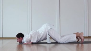 Pratik Yoga adam. Ashtanga kursuna katıldıktan sonra namaskara. Beyaz takım elbiseli oturuyor.