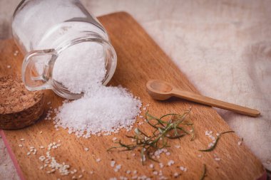 Ahşap zeminde deniz tuzu. Ahşap tabağa dökülen tuzluk yakın plan..