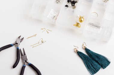 Kadın ellerine yakın çekim. Beyaz arka planda mücevher aletleriyle çalışan bir kadın. Stüdyoda yeşil püsküller yapan aletlerle çalışan bir mücevher tasarımcısı.. 