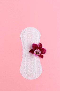 Pembe arka planda orkide çiçekli kadın hijyenik ped. Düz yatıyordu. Uzayı kopyala Jinekoloji ve hijyen kavramı ve kadın temizliği..