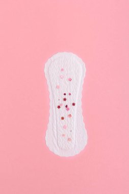 Beyaz hijyenik ped, üzerinde pembe parıltılı simler, kadın sağlığı konsepti. Pembe arka planda hijyenik ped. 