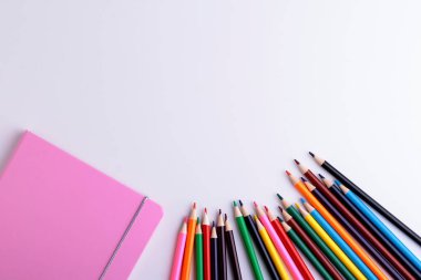 Beyaz arka planda pembe defterler ve renkli kalemler. Beyaz üzerine serin ekipman. Boşluğu kopyala.