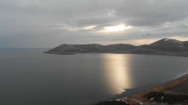 Soğuk Dağ Gölü Karlı Tepeler ile çevrili. Donmuş Alp manzarasının hava görüntüsü. Buzlu Suyu, Karla Kaplanmış Dağları ve Uzak Yaban Hayatı ile Kış Doğası Sahnesi.