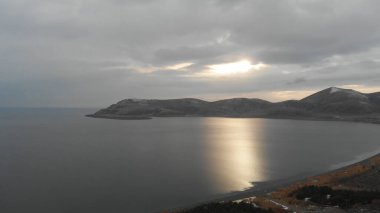 Soğuk Dağ Gölü Karlı Tepeler ile çevrili. Donmuş Alp manzarasının hava görüntüsü. Buzlu Suyu, Karla Kaplanmış Dağları ve Uzak Yaban Hayatı ile Kış Doğası Sahnesi.