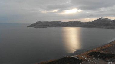 Soğuk Dağ Gölü Karlı Tepeler ile çevrili. Donmuş Alp manzarasının hava görüntüsü. Buzlu Suyu, Karla Kaplanmış Dağları ve Uzak Yaban Hayatı ile Kış Doğası Sahnesi.