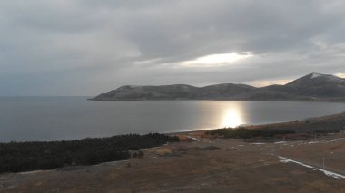 Soğuk Dağ Gölü Karlı Tepeler ile çevrili. Donmuş Alp manzarasının hava görüntüsü. Buzlu Suyu, Karla Kaplanmış Dağları ve Uzak Yaban Hayatı ile Kış Doğası Sahnesi.