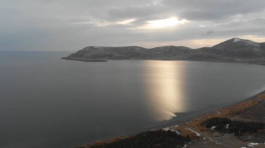 Soğuk Dağ Gölü Karlı Tepeler ile çevrili. Donmuş Alp manzarasının hava görüntüsü. Buzlu Suyu, Karla Kaplanmış Dağları ve Uzak Yaban Hayatı ile Kış Doğası Sahnesi.