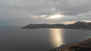 Soğuk Dağ Gölü Karlı Tepeler ile çevrili. Donmuş Alp manzarasının hava görüntüsü. Buzlu Suyu, Karla Kaplanmış Dağları ve Uzak Yaban Hayatı ile Kış Doğası Sahnesi.