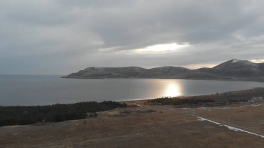 Soğuk Dağ Gölü Karlı Tepeler ile çevrili. Donmuş Alp manzarasının hava görüntüsü. Buzlu Suyu, Karla Kaplanmış Dağları ve Uzak Yaban Hayatı ile Kış Doğası Sahnesi.