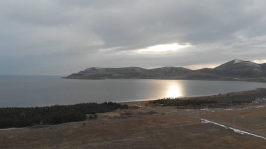 Soğuk Dağ Gölü Karlı Tepeler ile çevrili. Donmuş Alp manzarasının hava görüntüsü. Buzlu Suyu, Karla Kaplanmış Dağları ve Uzak Yaban Hayatı ile Kış Doğası Sahnesi.