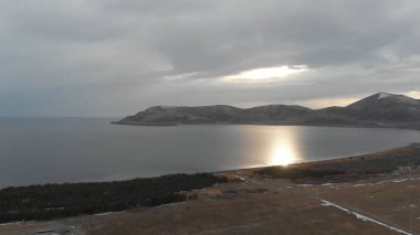 Soğuk Dağ Gölü Karlı Tepeler ile çevrili. Donmuş Alp manzarasının hava görüntüsü. Buzlu Suyu, Karla Kaplanmış Dağları ve Uzak Yaban Hayatı ile Kış Doğası Sahnesi.