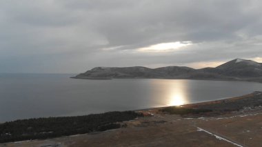 Soğuk Dağ Gölü Karlı Tepeler ile çevrili. Donmuş Alp manzarasının hava görüntüsü. Buzlu Suyu, Karla Kaplanmış Dağları ve Uzak Yaban Hayatı ile Kış Doğası Sahnesi.