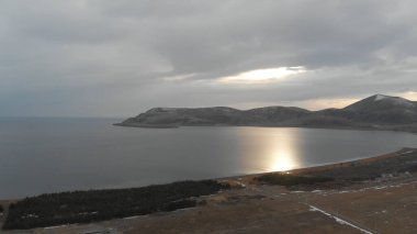 Soğuk Dağ Gölü Karlı Tepeler ile çevrili. Donmuş Alp manzarasının hava görüntüsü. Buzlu Suyu, Karla Kaplanmış Dağları ve Uzak Yaban Hayatı ile Kış Doğası Sahnesi.