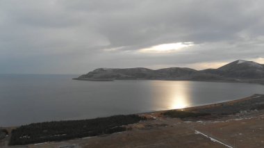 Soğuk Dağ Gölü Karlı Tepeler ile çevrili. Donmuş Alp manzarasının hava görüntüsü. Buzlu Suyu, Karla Kaplanmış Dağları ve Uzak Yaban Hayatı ile Kış Doğası Sahnesi.