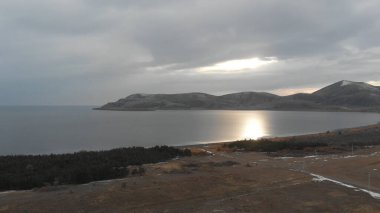 Soğuk Dağ Gölü Karlı Tepeler ile çevrili. Donmuş Alp manzarasının hava görüntüsü. Buzlu Suyu, Karla Kaplanmış Dağları ve Uzak Yaban Hayatı ile Kış Doğası Sahnesi.