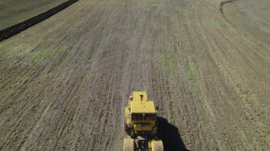 Çiftlik arazisinde traktör, tarlada çalışan sarı tarım makinesi, kırsal tarım ve hasat süreci, modern tarım, ağır makineler ve kırsal arazi konsepti