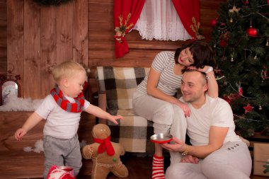 Anne ve baba çocuğunu Noel dekorasyonu ile oynarken