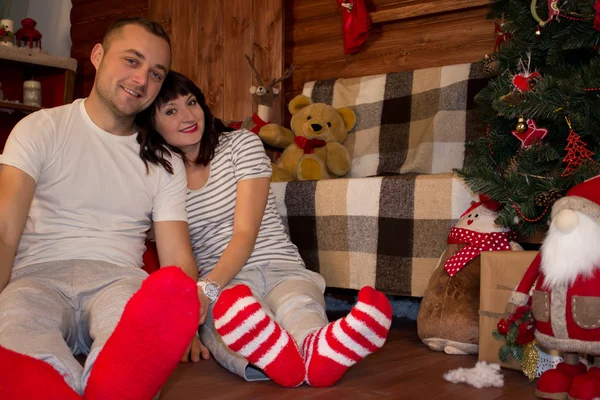 Feliz joven familia sentada cerca del árbol de Navidad — Foto de Stock