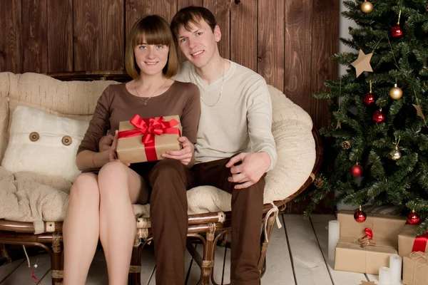 Joven hombre y mujer se sienta cerca del árbol de Navidad — Foto de Stock