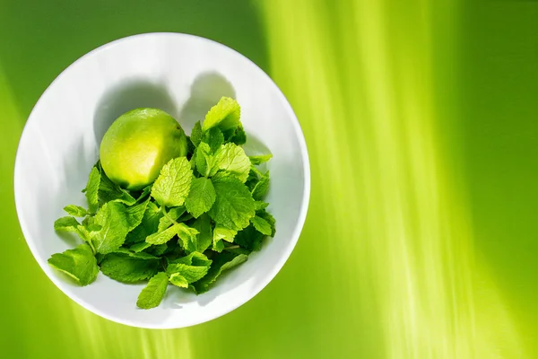 Lima fresca con menta en taza blanca sobre fondo verde — Foto de Stock