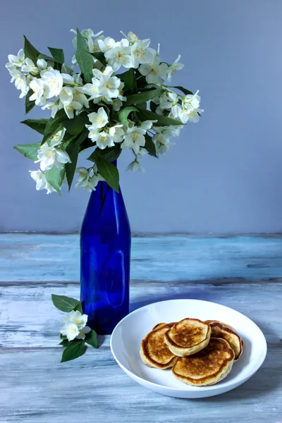 Pancakes for brekfast near beautiful white flowers in bottle — Stock Photo, Image