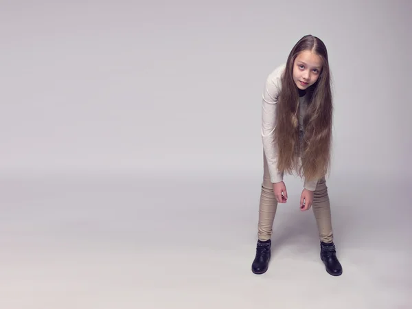 Divertida adolescente vestida a la moda de pie sobre un fondo gris — Foto de Stock