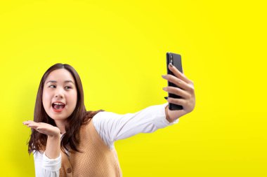 Mutlu güzel kız sarı arka planda akıllı telefondan kendi portresini yapıyor..