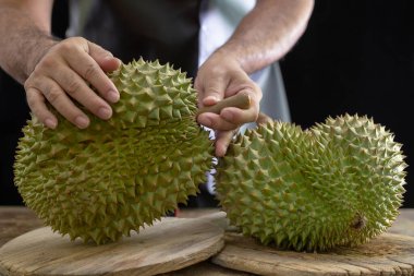Erkekler el ele tutuşur Meyvelerin kralı Durain tahta arka planda.