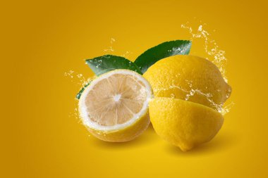 Sarı arka planda izole edilmiş dilimlenmiş limon meyvesine su sıçraması