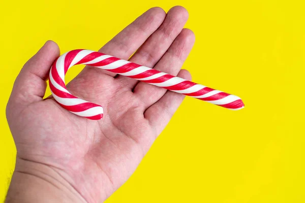 Parlak ve neşeli sarı arka planda elinde Noel bastonu.