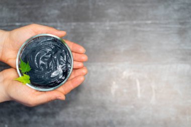 Kadın ellerinde kavanozdaki kömür kremi. Güzellik merkezi, cilt bakımı yüz maskesi konsepti