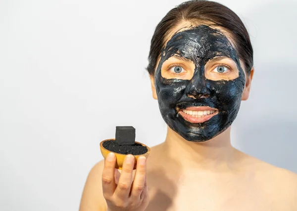 Emotional Woman with black charcoal face mask and friable coals in her hands.