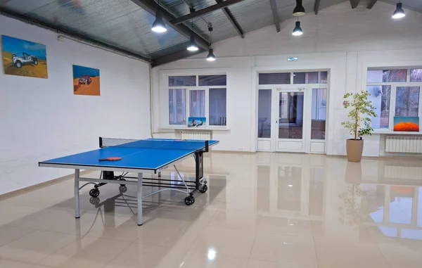 Tenis masası ve parlak zemini olan bir oda..