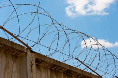 Tepesinde Egoza dikenli teli olan bir duvar..