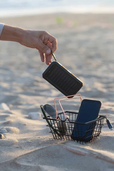 男はビーチにサングラスとケーブルUsb付きの小さなショッピングカートにポータブルソーラーパネルを置きます オンラインストア ショッピングタイムコンセプト — ストック写真